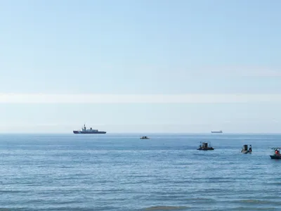 A zoomed-out view of big and small boats on a wide open blue water