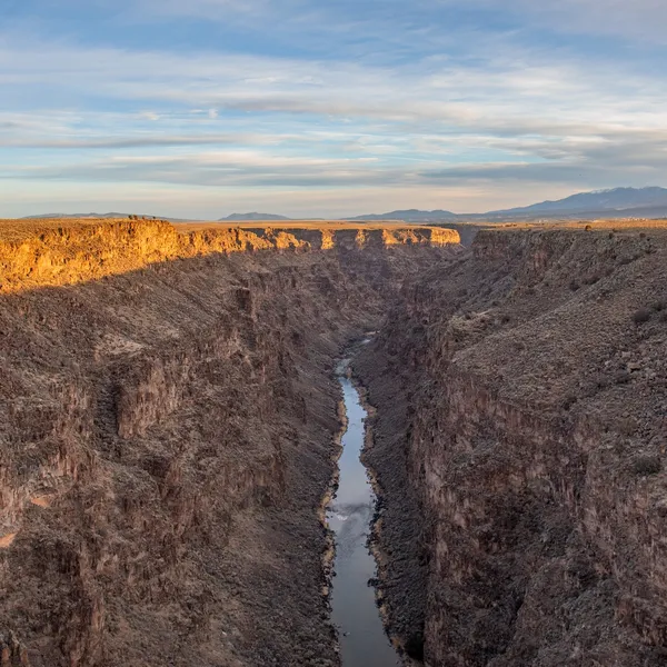Sun shines on a deep gorge with a river at the bottom
