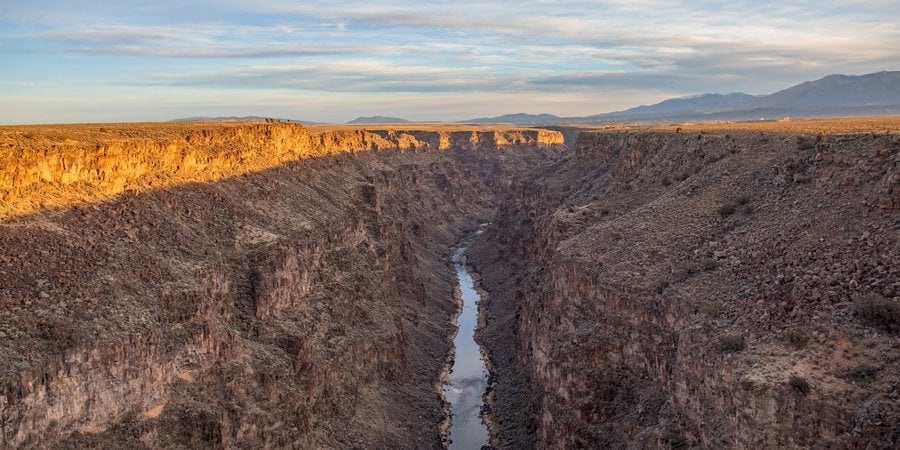 Sun shines on a deep gorge with a river at the bottom