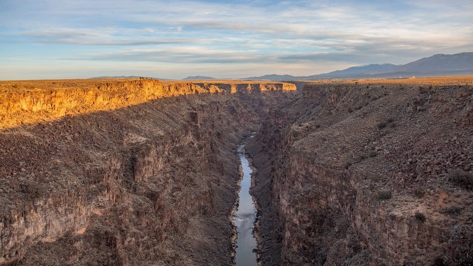 Sun shines on a deep gorge with a river at the bottom