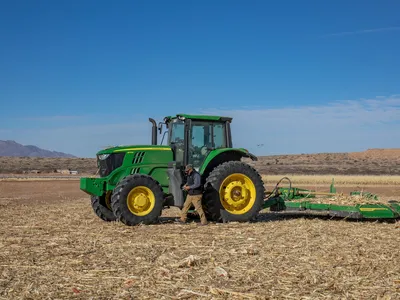 A tractor drives across a dry field