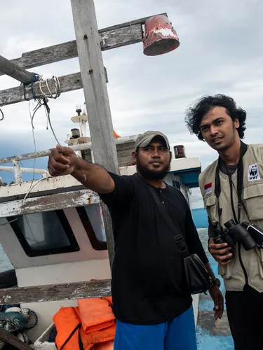 Two men stand on a small boat