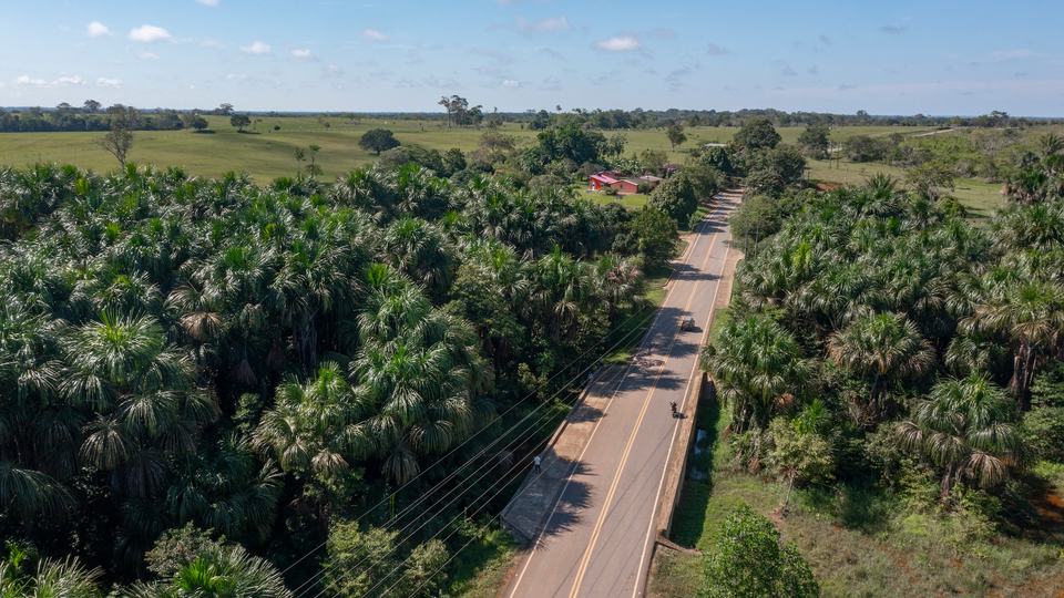 A paved road cuts through a lush green landscape