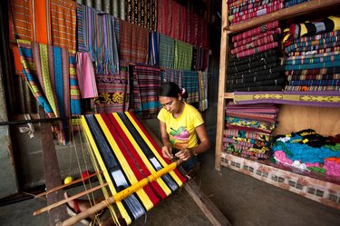 A woman in East Timor weaves a tais (a local woven fabric) at a market