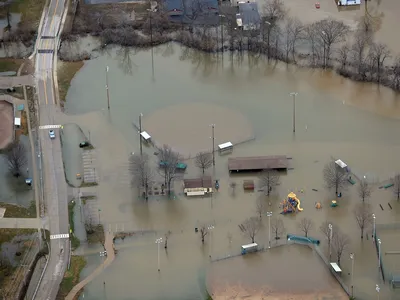 An aerial view of brownish grey water flooding homes and a road