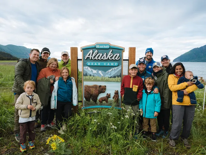 A group of people posing at the bear camp welcome sign
