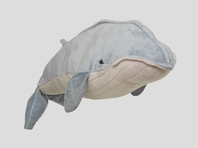 A blue whale plush against a gray background
