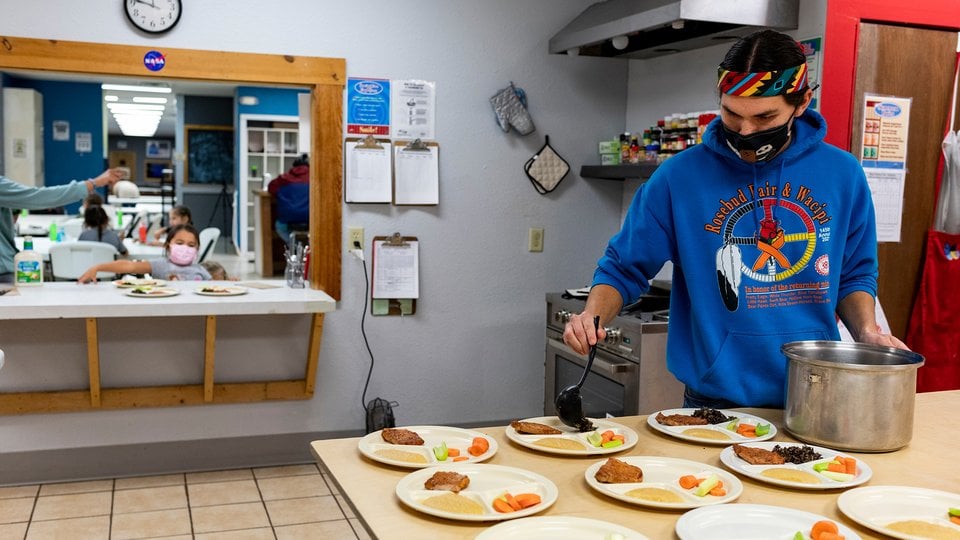 Indigenous man fills plates in kitchen