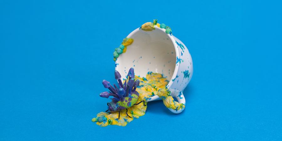 A sculpture of a teacup with a colorful bug