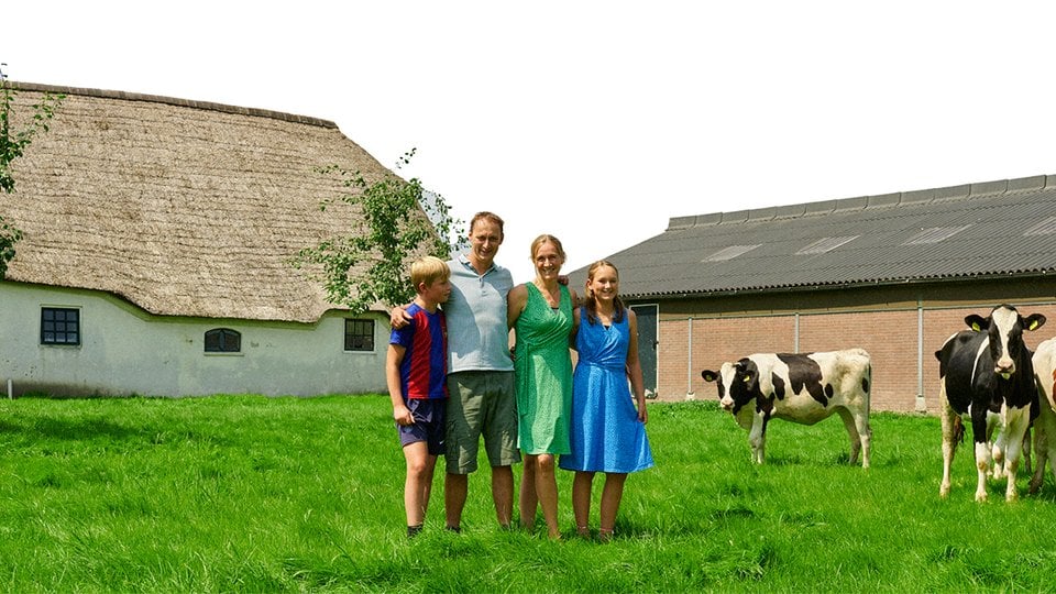 Family poses in front of their farm
