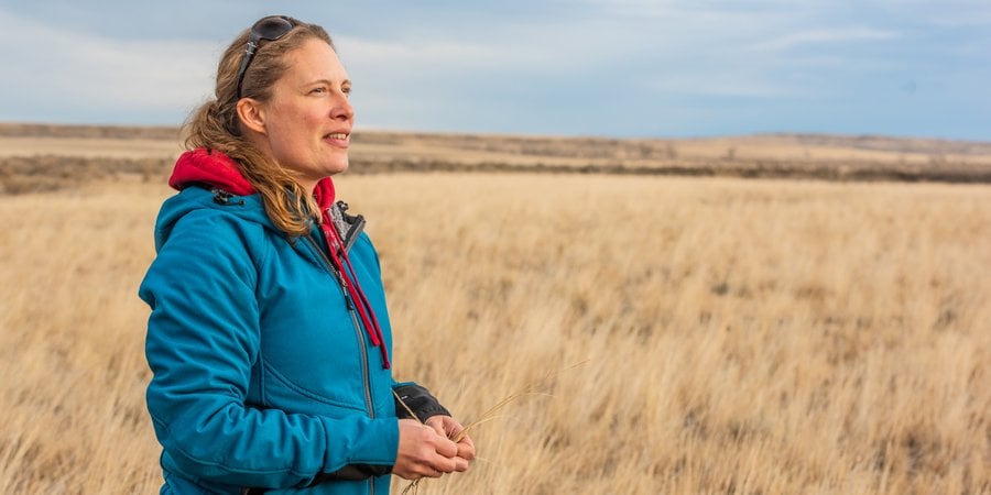 A woman stands looking out onto the prairie