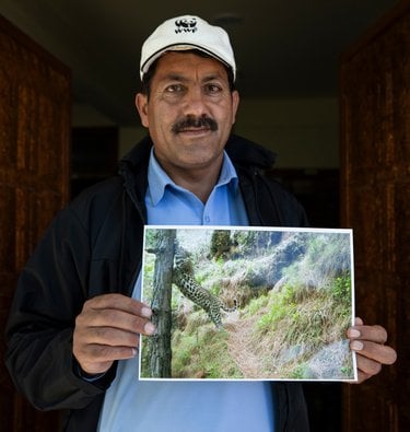 A man holds up a photo of a leopard
