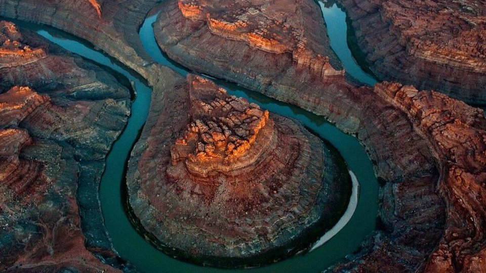 Red canyons with a blue river spiraling through it.