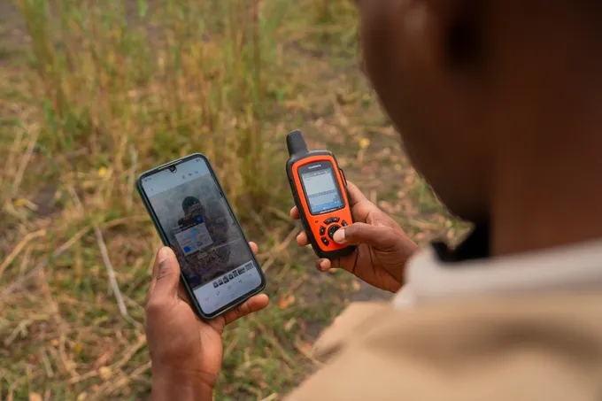 Hands holding a smartphone and a GPS device