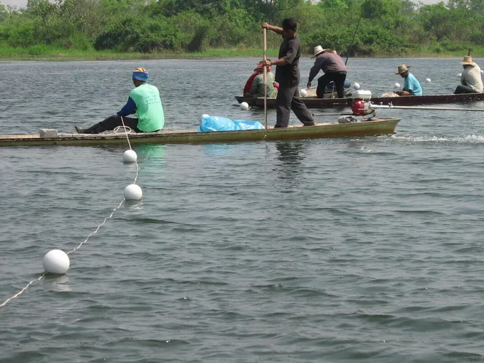 People in boats on a river laying out a rope