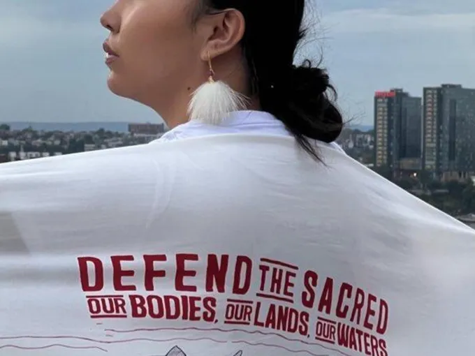 Charitie Ropati wears a white flag with red lettering over her shoulders