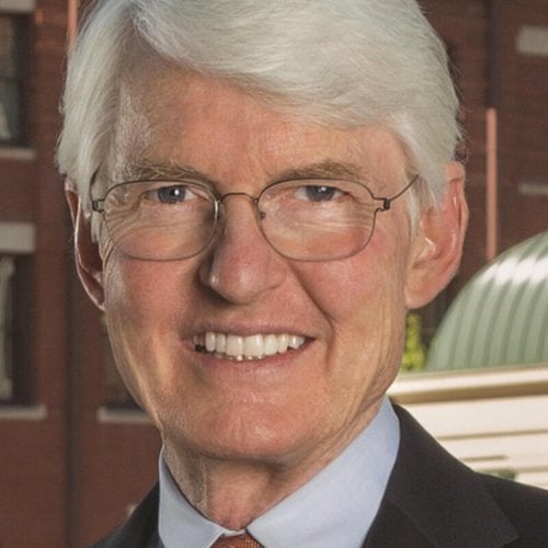 An older white man with gray hair and rectangle metal glasses smiles.