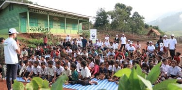 Local community members in Laos sit on blankets in the village common area laid out to discuss a tree planting and forest management program