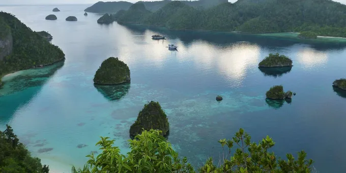 Aerial view of the Raja Ampat Islands dotting clear, shallow waters.