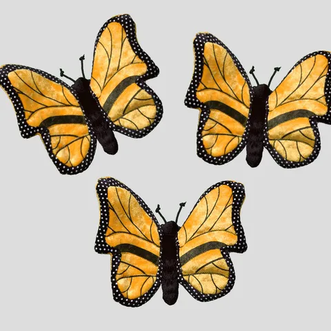 Three monarch butterfly plush against a gray background