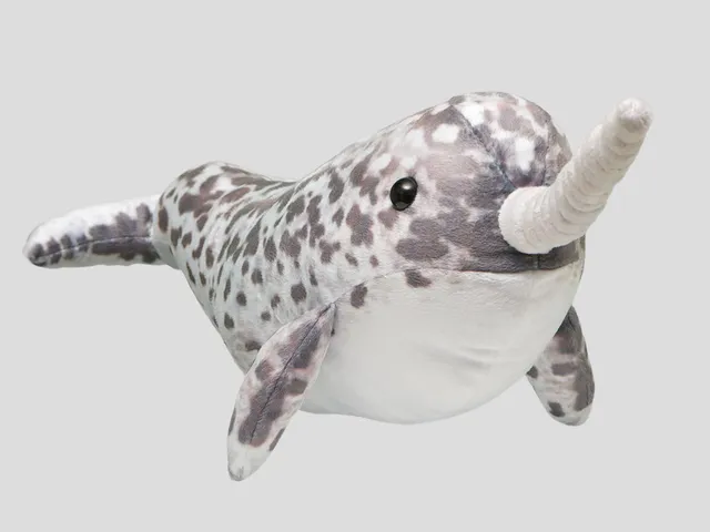 A narwhal plush against a gray background