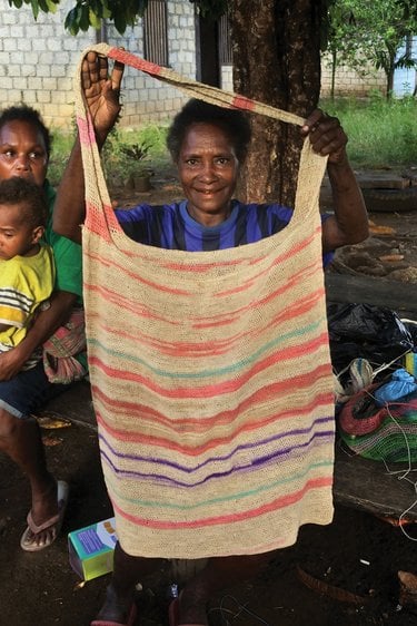 Woman holding up noken bag