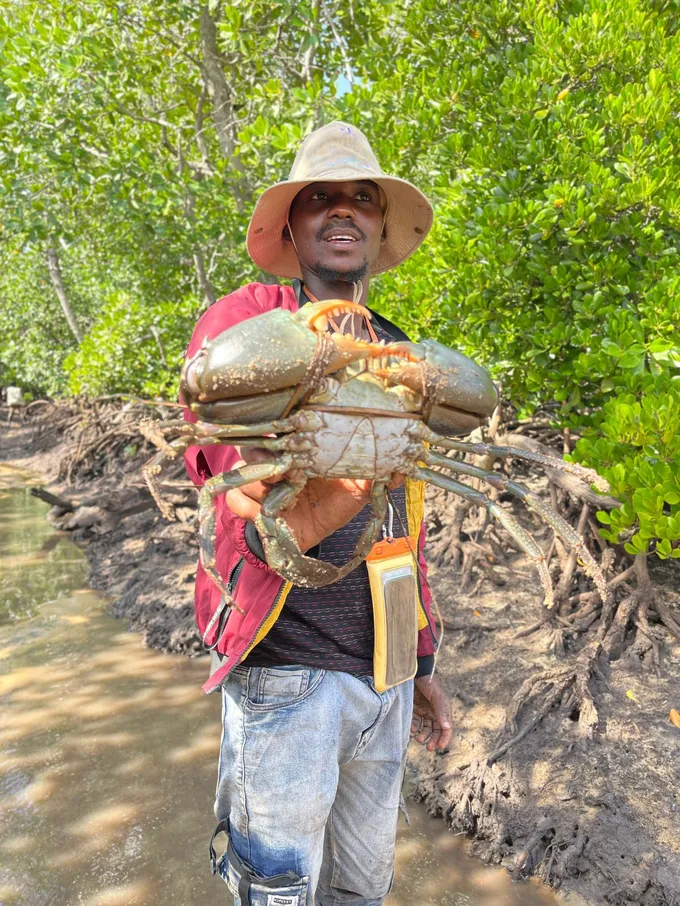 A man holds out a large shellfish he has caught