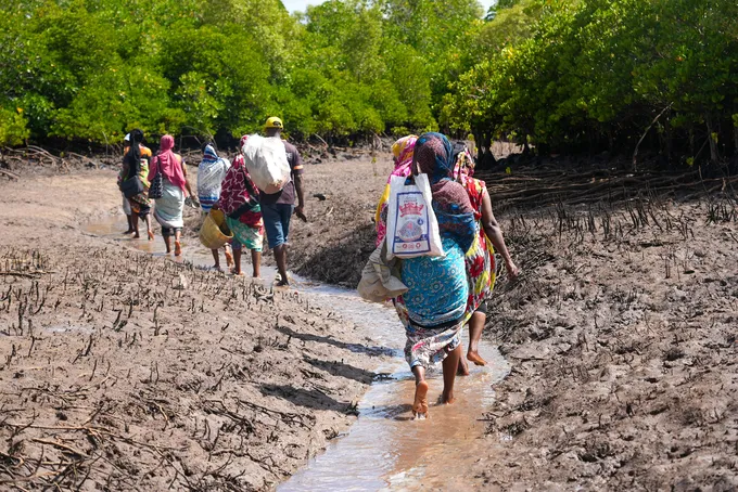 People walking away through a muddy trench