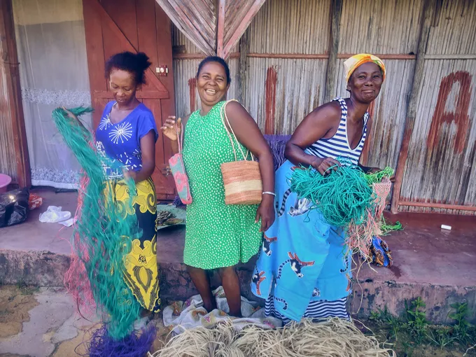 Three women in colorful clothing smile at camera