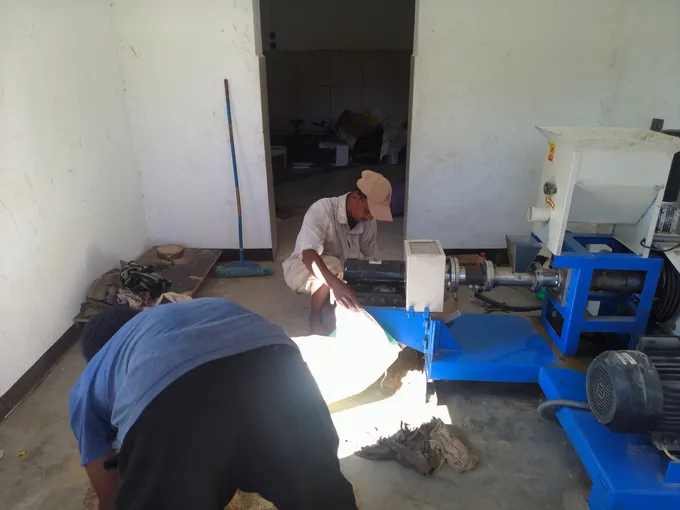 Two men kneeling in a room working with a machine