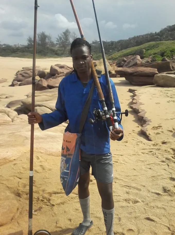 A man stands on the beach with fishing gear