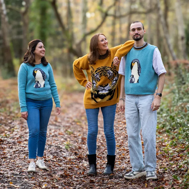 Three people wearing sweaters walking in the woods