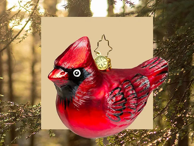 A red bird ornament against a background of winter trees