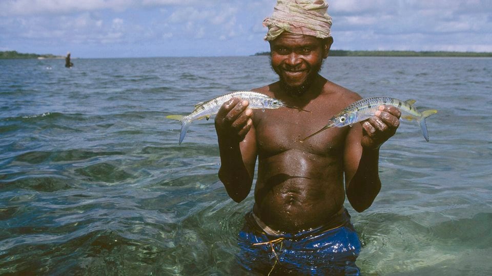 Man holding two fish while standing in the water