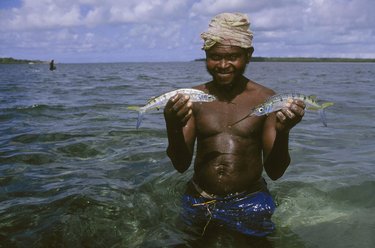 Man holding two fish while standing in the water