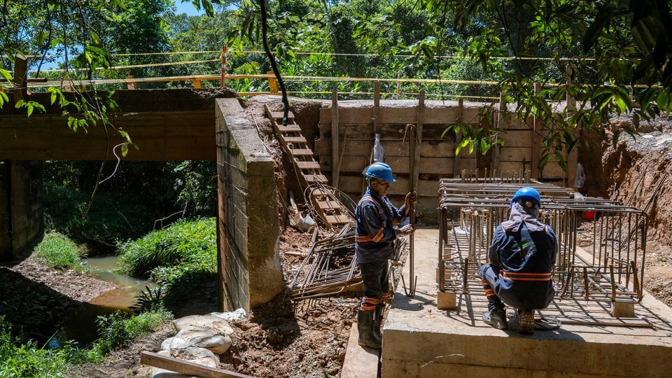 Two workers working on underpass in wooded area
