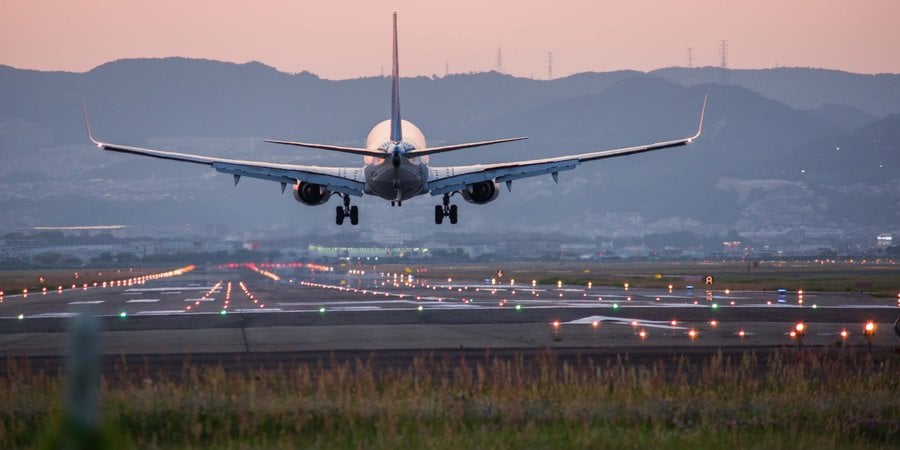 Plane flying right above a runway with hills in the background
