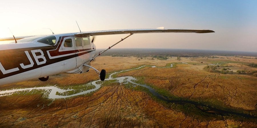 Photo of an airplane in flight over savanna landscape