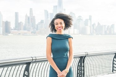 Alexa White stands in front of a river and city skyline smiling at the camera