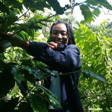 Alexa White smiles while surrounded by lush greenery