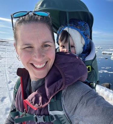 Selfie of woman with baby in carrier in snowy landscape