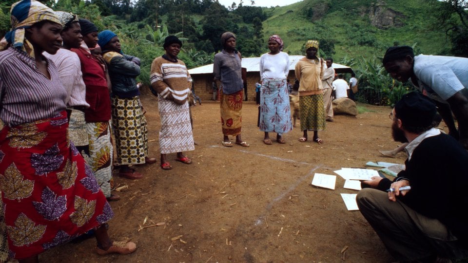 Oku women gathered outside, with lush green hills behind them. An Oku community resource mapping exercise designed to determine which tree species the women prefer to use for their firewood.
