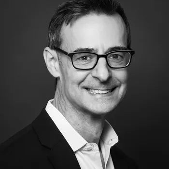 Black and white headshot of Andrew smiling at the camera.