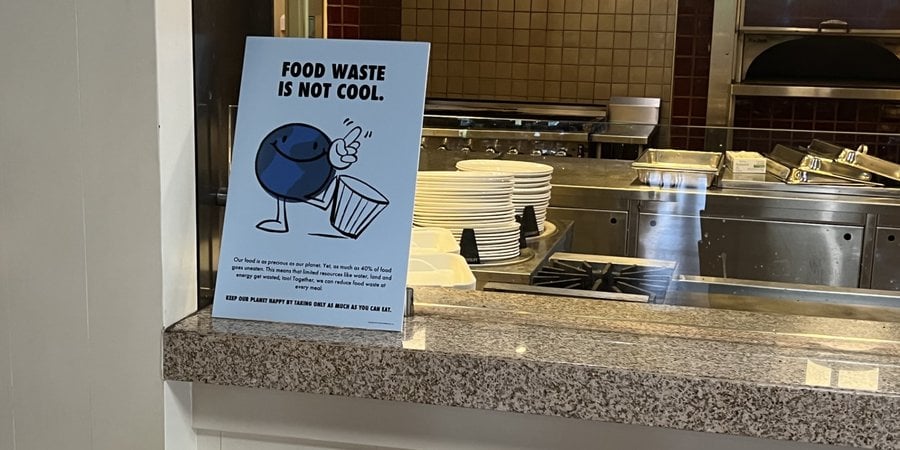 Sign by a serving station reading "food waste is not cool"