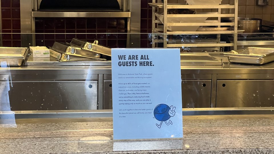 sign at cafeteria serving station reads, "we are all guests here"