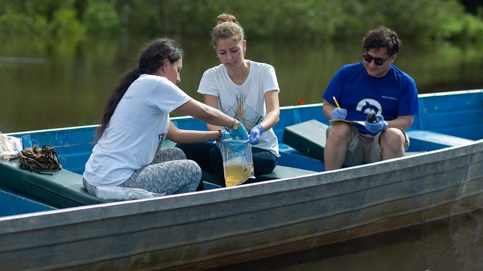 Three people in boat testing water