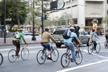 Commuters bike to work in city Environmentally conscious bikers cycling in traffic in San Francisco, California, United States