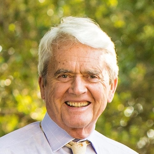 Headshot of an older white man wearing a yellow tie and white button down.