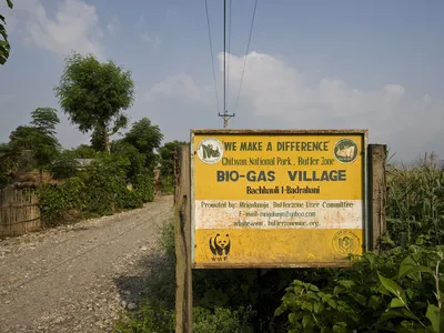 A large sign indicating the Bio-gas village in Chitwan National Park buffer zone. Nearly 90 % of the village had bio gas installed, funded by WWF. Villages used to use firewood for their cooking, but now use bio gas instead. This is not only a cleaner met