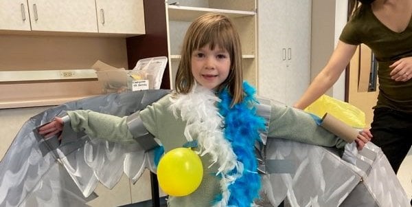 A child dresses up as a seabird wearing a bunch of feathers